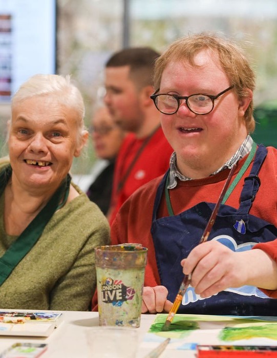 Two people smiling and painting