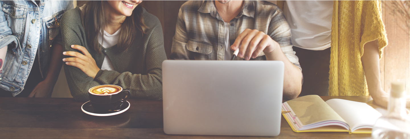 People looking at the laptop on a rustic worktop