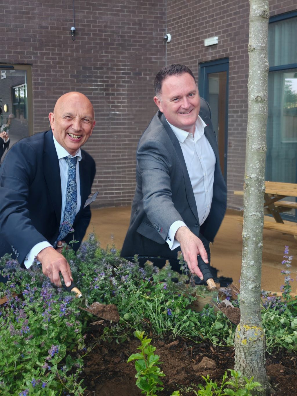 Two people leaning over a planter