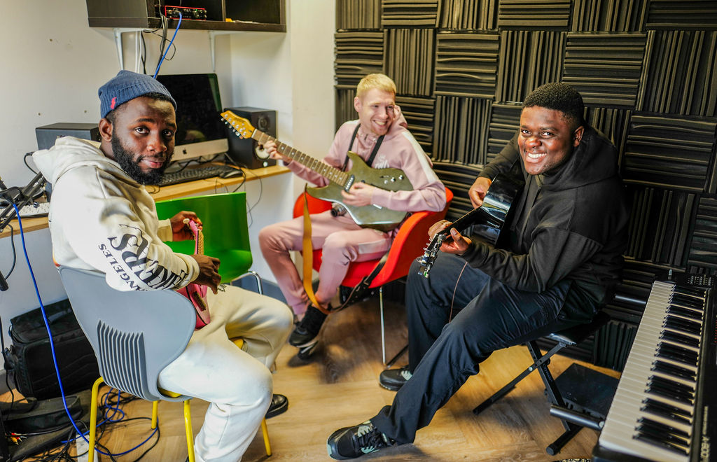 Three young people sit with instruments
