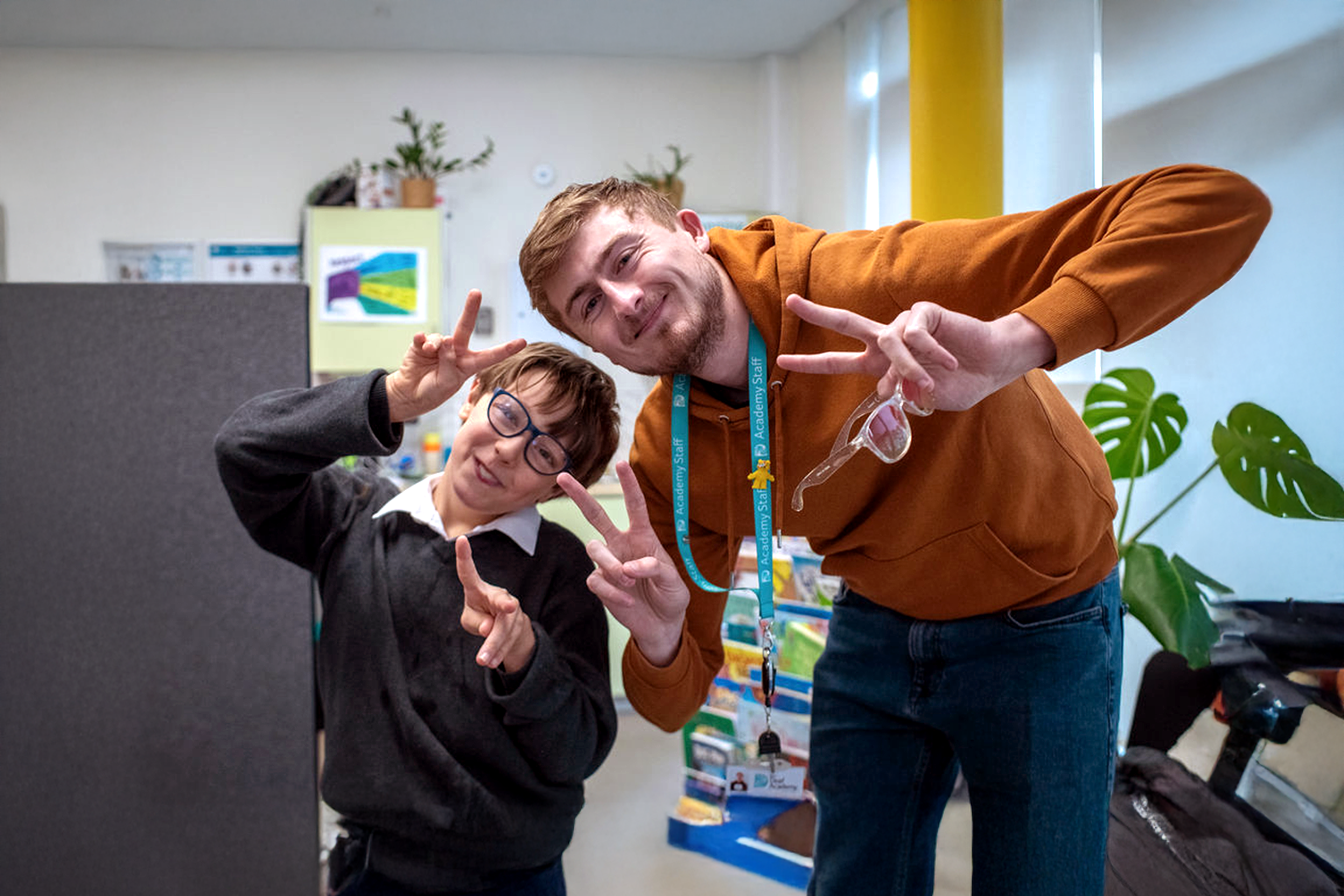 Charity worker and child doing victory signs with their hands.